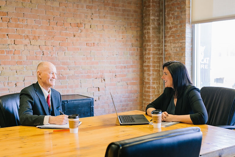 Man and Woman in board room having a meeting in person and smiling